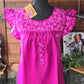 Hot pink ruffled blouse with flower appliqué